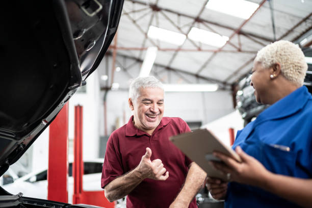 Happy customer talking to mechanics in auto repair Car mechanics, workers, customers, satisfaction / Auto car repair service center. auto repair shop mechanic digital tablet customer stock pictures, royalty-free photos & images