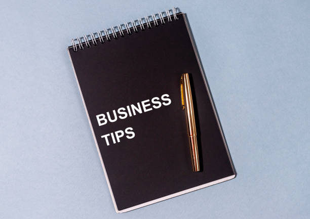istock inscription business tips on a black notebook, gold pen on a gray-blue background 1221393125