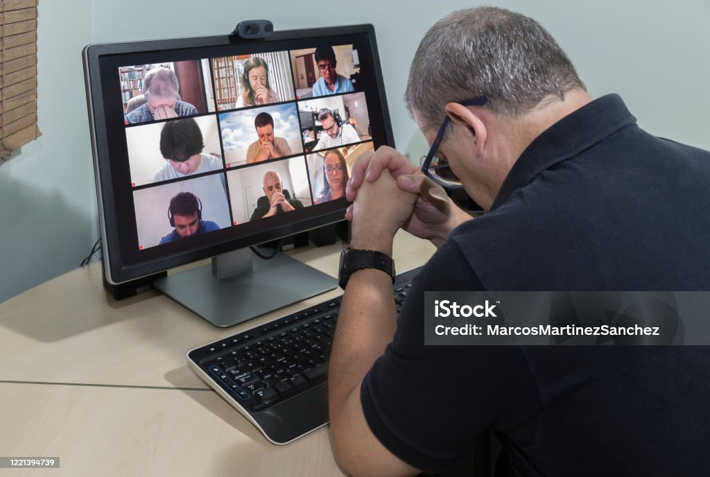 Friends in their homes on a conference call and praying together for the good of all - lowering the head Great example of how technology can facilitate social distance during crises that require staying at home.   Case of during pandemic isolation by COVID-19. Praying Stock Photo