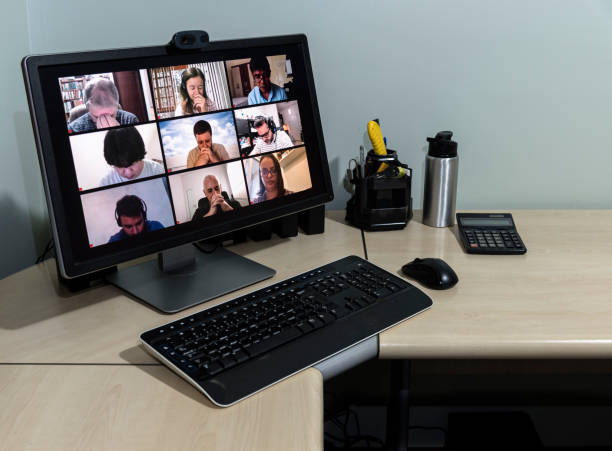 istock Empty workstation with computer screen just showing image of friends in their homes on a conference call and praying together for the good of all 1221394742