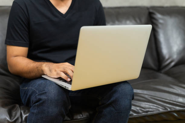 istock Close up male hands using laptop work from home sofa 1221397693
