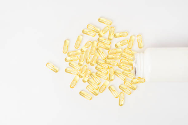 istock Heaps of yellow vitamins pills on white background 1221398616