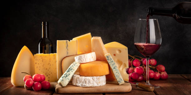 panorama del formaggio, formaggi mvari con uva e vino versato, una vista laterale su sfondo scuro con un luogo per il testo - wine cheese food cellar foto e immagini stock