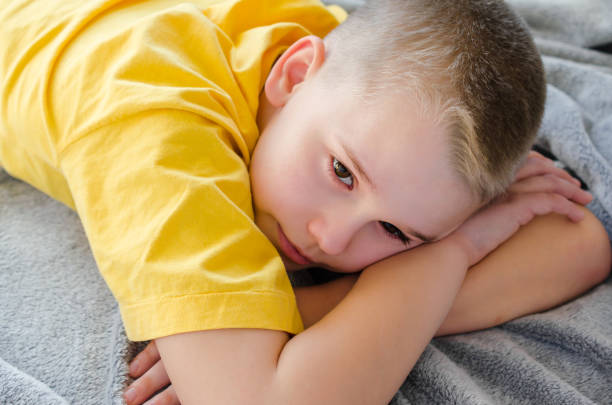 istock Blond boy dreams or thinks while lying on sofa at home. Rest in daytime. Stay at home. Isolation. Quarantine. 1221403150