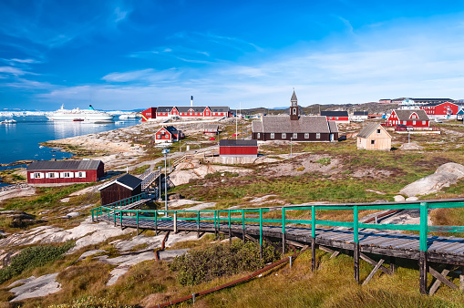 Ilulissat, Greenland - August 16, 2012: View of the city center with a cruise ship docked. Ilulissat, formerly Jakobshavn, is the municipal seat and largest town of the Avannaata municipality in western Greenland, located approximately 350 km (220 mi) north of the Arctic Circle. It is the third-largest city in Greenland, after Nuuk and Sisimiut.