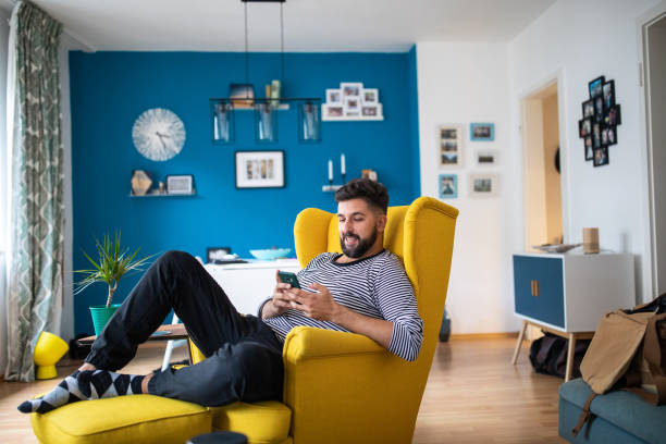 istock Happy bearded man relaxing and sending text messages at modern living room 1221410366