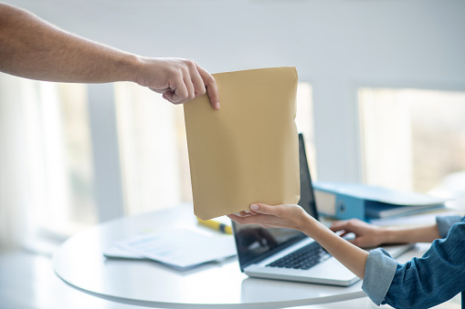 At work. Close-up of female hands taking envelope from male hands