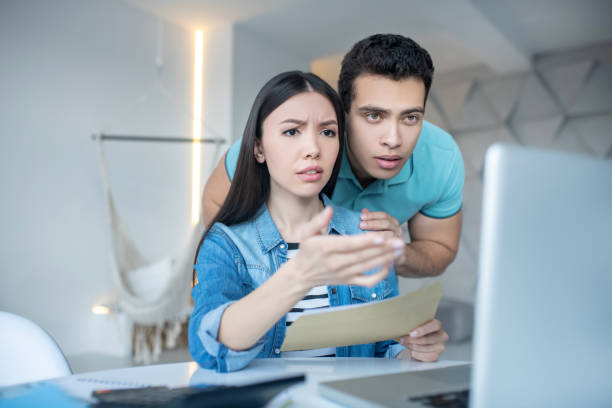 istock Brunette male and dark-haired female checking something on laptop, looking concerned 1221411191