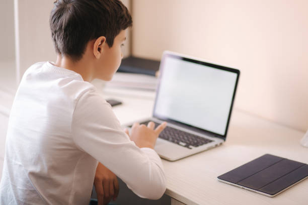 istock Schoolboy at home using laptop when studying. Teenage boy make homework on quarantine. Mockup 1221417475