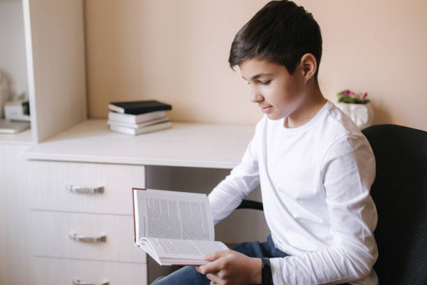 istock Young boy sitting by the desk and read the book. Study at home during quarantine 1221418217