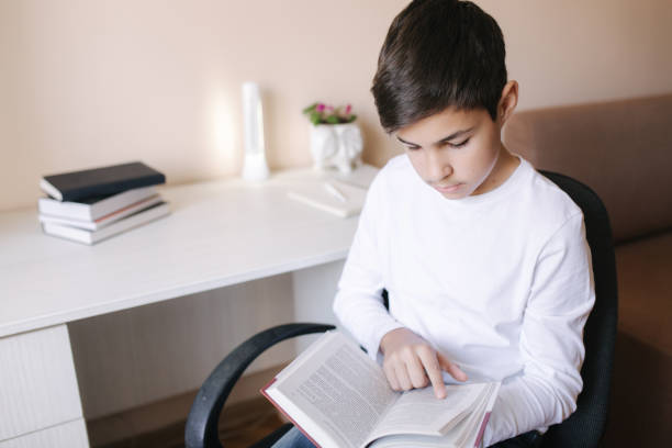 istock Young boy sitting by the desk and read the book. Study at home during quarantine 1221418272