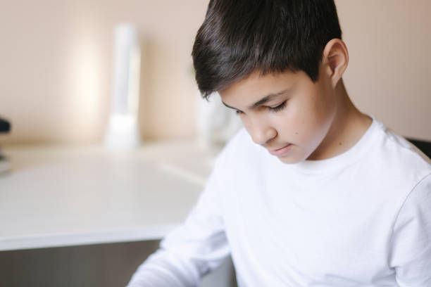 istock Young boy sitting by the desk and read the book. Study at home during quarantine 1221418345