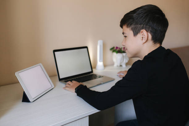 istock Teenage boy studying on laptop and watching something on tablet. Young boy use two device in same time. Working on laptop and tablet 1221418619