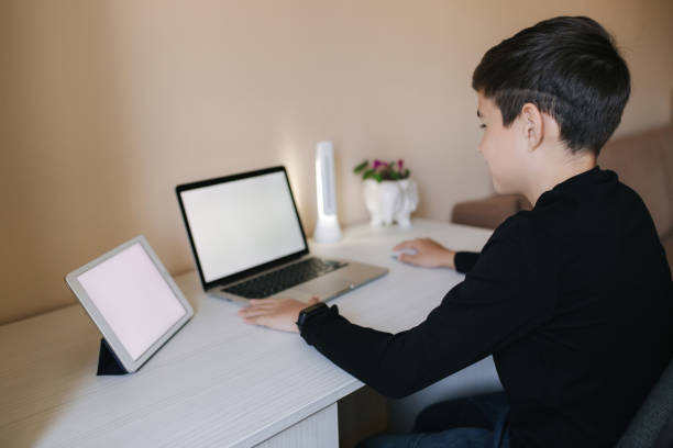 istock Teenage boy studying on laptop and watching something on tablet. Young boy use two device in same time. Working on laptop and tablet 1221418644