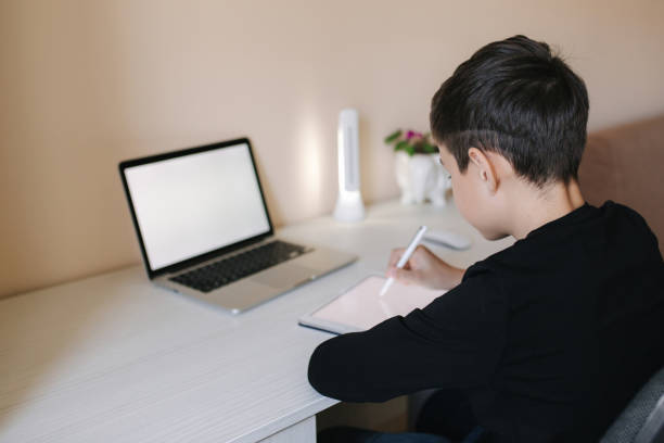 istock Handsome young boy drawing on tablet at home. Teenage boy use tablet for work. Schoolboy study at home using tablet, laptop, smartphone 1221418791