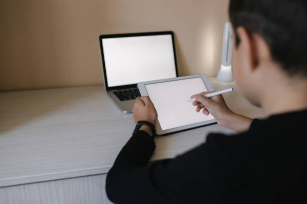 istock Handsome young boy drawing on tablet at home. Teenage boy use tablet for work. Schoolboy study at home using tablet, laptop, smartphone 1221418842