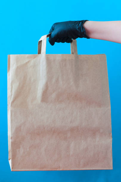 istock Cropped hands with black gloves hold craft paper bag. 1221419006