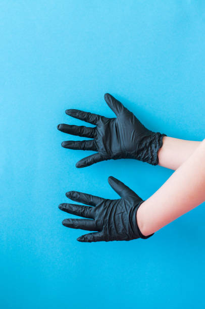 istock Hands with black gloves on blue background. 1221419010