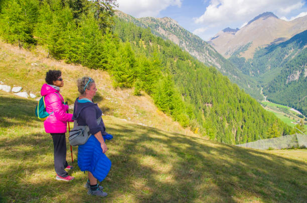 two young female hikers walk happily on mountain paths and admire the view during their holidays