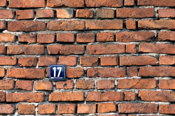 Number seventeen, a metal sign on a red brick wall of a house.