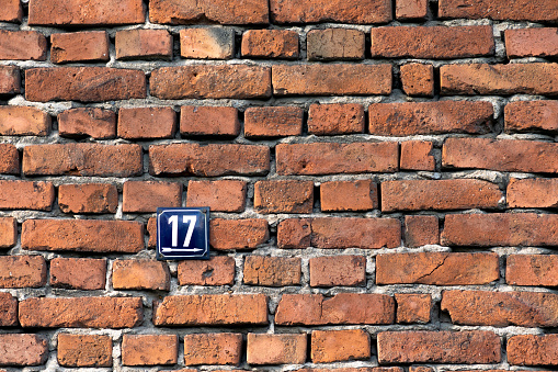 Number seventeen, a metal sign on a red brick wall of a house.