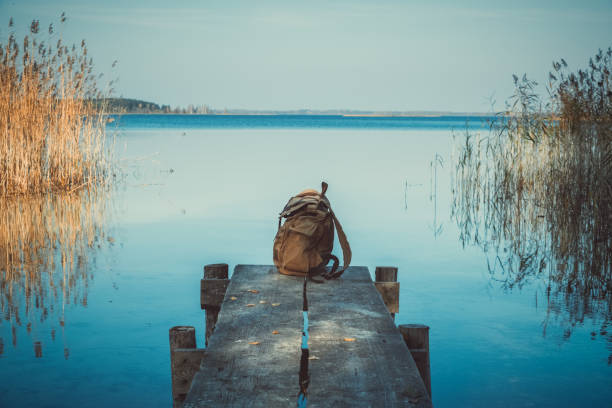 Backpack of traveller on wooden pier on blue summer lake. Backpack of traveller on wooden pier on blue summer lake. braslav lakes stock pictures, royalty-free photos & images
