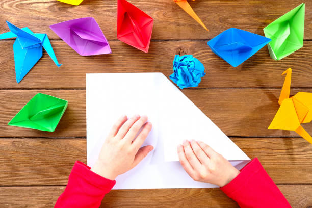 istock The child makes origami from colored paper on the table. Creativity concept. 1221424148