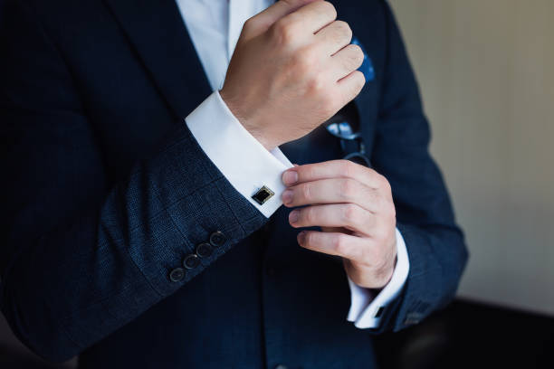 Close-up of a man in a tux fixing his cufflink. stock photo