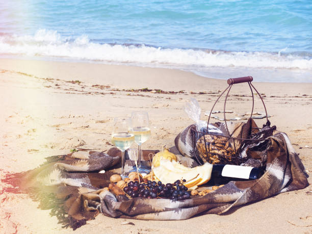 Composition of white wine, fruit and nuts on sandy beach near the sea