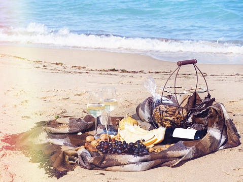 Romantic composition of white wine, fruit and nuts on a beach  in a sunny day