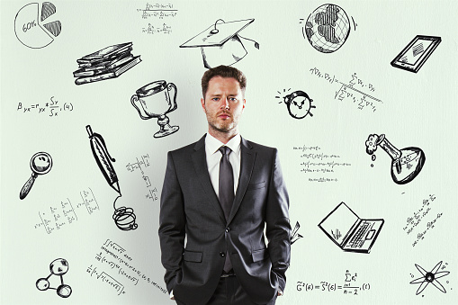 Learn and technology concept. Portrait of attractive thoughtful young businessman standing on white concrete wall background with business sketch