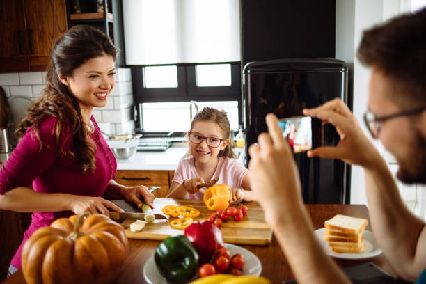 istock Father photographing family at table in kitchen 1221426367