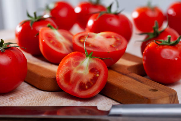 istock Cut fresh tomatoes on wooden table in home kitchen 1221426451