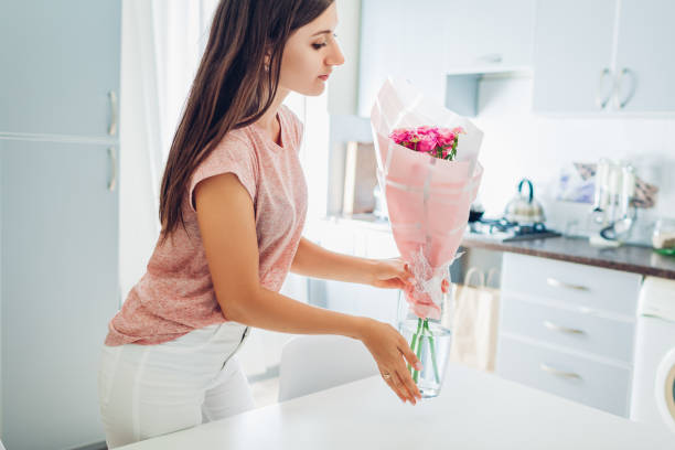 kobieta stawia wazon z kwiatami. gospodyni dba o przytulność w kuchni. nowoczesny projekt kuchni - flower gift decoration domestic room zdjęcia i obrazy z banku zdjęć