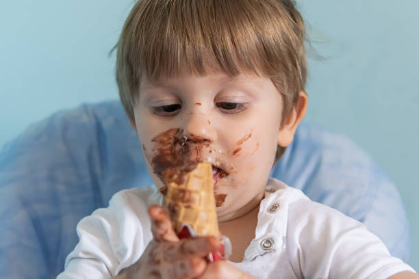 kleiner junge mit schokoladeneis auf gesichtgeschmiert. kleiner junge isst eis - child chocolate ice cream human mouth stock-fotos und bilder