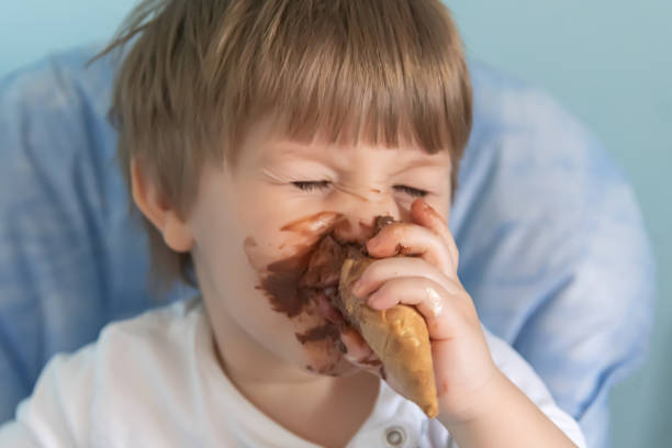 kleiner junge mit schokoladeneis auf gesichtgeschmiert. kleiner junge isst eis - child chocolate ice cream human mouth stock-fotos und bilder
