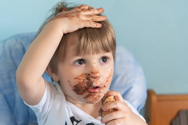 kleiner junge mit schokoladeneis auf gesichtgeschmiert. kleiner junge isst eis - child chocolate ice cream human mouth stock-fotos und bilder