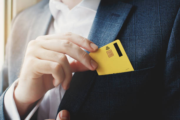 Man putting credit card in suit pocket stock photo