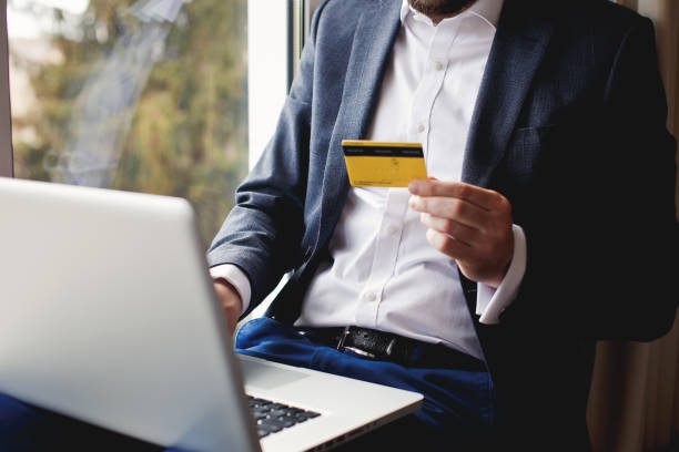 Mens hand holding credit card and using laptop. Online shopping. stock photo