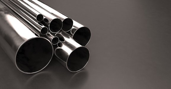 Stack of stainless steel tubes and pipes of various sizes and diameters, with chrome finish, laying on a dark background with copy space on right side. Warehouse samples. Construction industry and metalware. Digitally generated image.