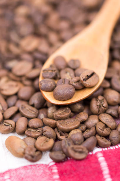 Coffee beans on the wooden spoon macro closeup.