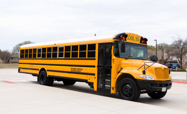 istock Large, clean school bus parked by curb at school 1221435667
