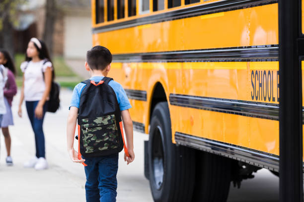 istock Rear view photo tired boy walking away from school bus 1221435713