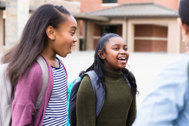 istock Beautiful schoolgirl laughing while talking with friend 1221435810