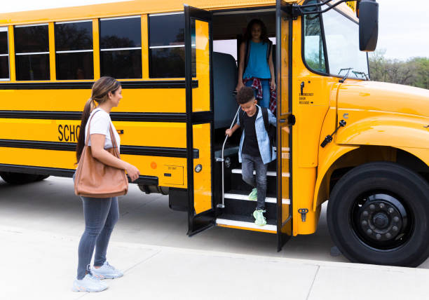 istock Mid adult mom greets her son at school bus stop 1221435881