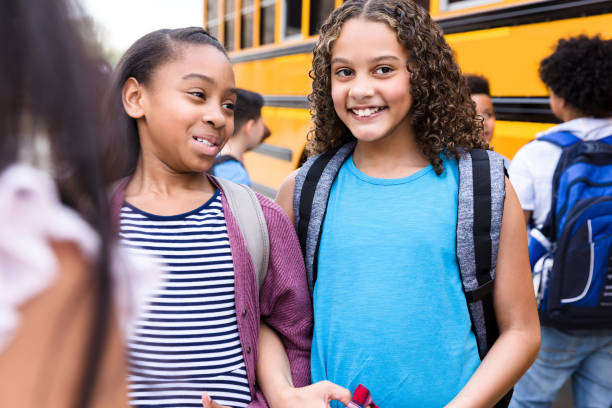 istock Happy schoolgirls wait for bus together 1221435924