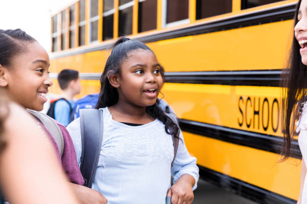 istock Happy schoolgirls talk before getting on school bus 1221435929