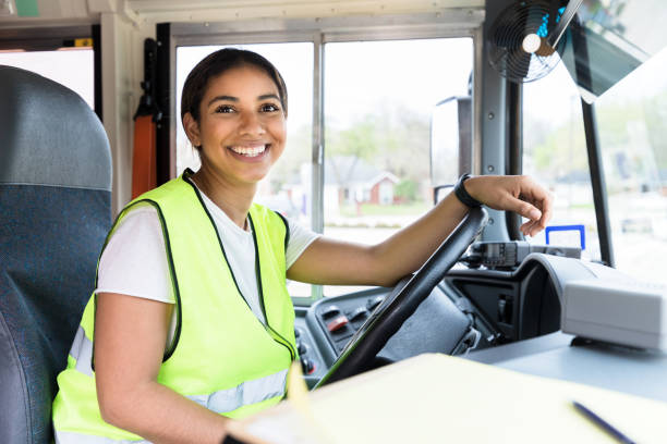 스티어링 휠 뒤에 앉아, 운전자는 카메라를 위해 미소 짓는다. - school bus education transportation school 뉴스 사진 이미지