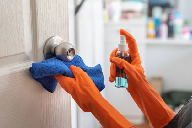la femme porte la porte de nettoyage de gants en caoutchouc orange, poignée de porte avec le jet d’alcool à la maison. - doorknob photos et images de collection