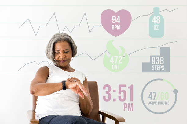 Senior woman looking at smart watch An active African American senior woman checks activity level and health status on her smart watch. Heart rate, water consumption, steps taken, activity level and the current time are overlaid in a digitally generated image. wearable computer photos stock pictures, royalty-free photos & images